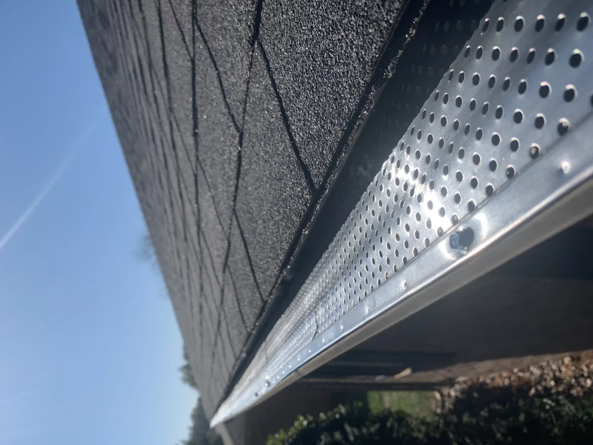 Gutter guard installation in Vancouver, BC — perforated metal gutter guard fitted along the edge of an asphalt shingle roof