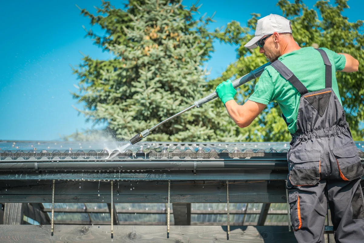 Roof and gutter cleaning in Vancouver, BC — technician washing a roof surface on a sunny day